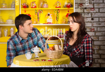 Junge weiße Paar in karierten Hemden suchen einander an der Snack-Bar mit einem Datum. Stockfoto