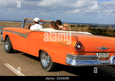 Touristen Reisen in einem klassischen Cabrio Oldtimer entlang Malecon in Havanna, Kuba Stockfoto