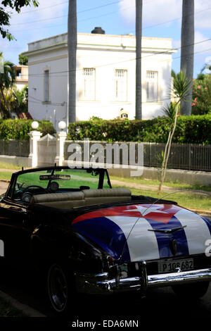 Ein Cabrio amerikanische Oldtimer mit der kubanischen Flagge gemalt - in Havanna, Kuba vor einer großen villa Stockfoto