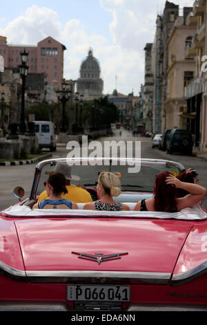 Touristen Reisen in einem klassischen Cabrio Oldtimer in Havanna, Kuba mit dem Capitolio Nacional im Hintergrund Stockfoto