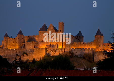 Carcassonne, befestigte Westseite um Chateau Comtal, bei Einbruch der Dunkelheit beleuchtet. Südwest-Frankreich. Stockfoto