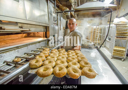 Eine frische Ladung von heißen New Yorker Stil Sesam Bagels werden entfernt, aus dem Backofen an der berühmten Manhattan H & H Midtown Bagels East Stockfoto
