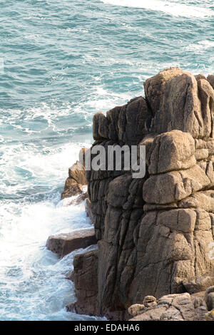 Wellen brechen sich am Felsen bei Porthcurno, Cornwall, England an sonnigen Herbsttag Stockfoto