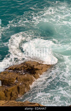 Wellen brechen sich am Felsen bei Porthcurno, Cornwall, England an sonnigen Herbsttag Stockfoto