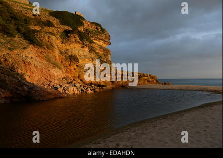 gelbe farbige Klippen am Figuiera Strand in der untergehenden Sonne glühen Stockfoto