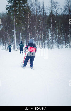 Jungen, die Spaß am Kick Schlitten in Lappland Stockfoto