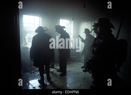 USA, SOUTH BRONX, NEW YORK CITY - AUGUST 1977. New York City Feuerwehrmann in geräucherten füllen Raum bei Brand in verlassenen Mietshaus Block. Stockfoto