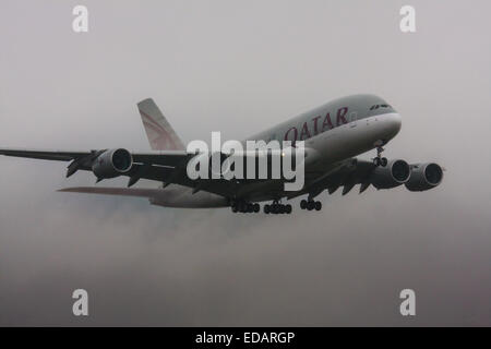 3. Januar 2015, Heathrow Airport, London. Niedrige Wolken und Regen bieten ideale Voraussetzungen Gefolge Wirbel und "Flusen" kondensiert Feuchtigkeit über die Flügel von landenden Flugzeuge zu beobachten. Mit der Start-und Landebahn sichtbar nur in letzter Minute mussten mehrere Flugzeuge ein "Go-Round", Verzicht auf ihre ersten Versuche landen zu leisten. Bild: Mit Wasser hereinkommt streaming aus seiner Steuerflächen ein Qatar Airbus A380 auf Heathrows Start-und Landebahn 27 L landen. Stockfoto