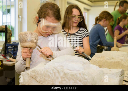 Schülerinnen und Schüler arbeiten an Stücke von Sandstein in einer Schule der Künste für Kinder. Stockfoto