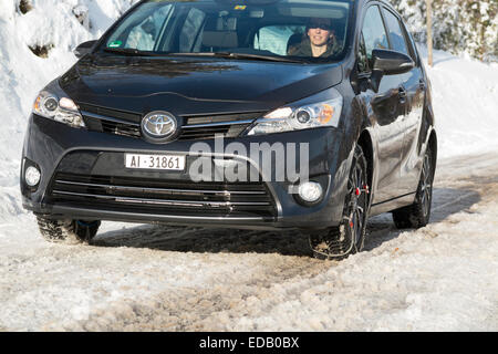 Frau Treiber Autofahren ausgestattet mit Schneekette / Ketten am vorderen Rad / Räder und Winterreifen / Reifen. Stockfoto