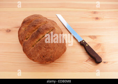 Frisch gebackene kernigen Brot mit einem Brotmesser auf einem Holztisch Stockfoto