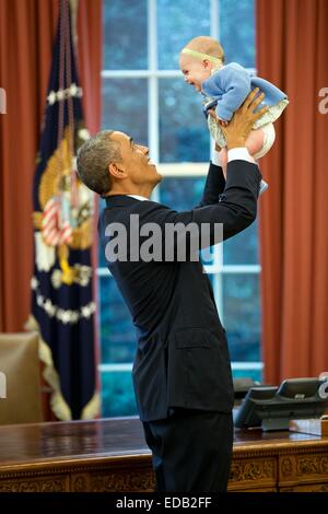 US-Präsident Barack Obama mit einem Baby eines ausgeschiedenen Bediensteten im Oval Office des weißen Hauses 14. Oktober 2014 in Washington, DC spielt. Stockfoto