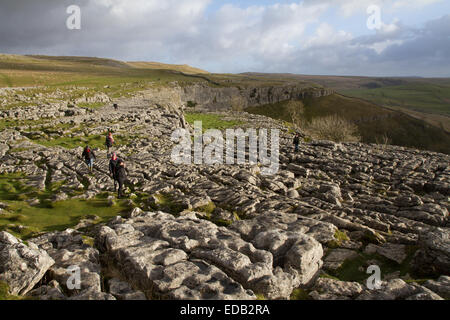 Wanderer durchqueren die Kalkstein-Pflaster über Malham Cove Stockfoto