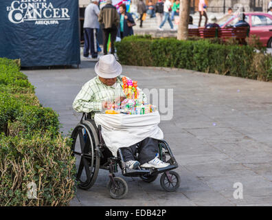 Peruanische Lebensstil und Armut: Behinderte Mann im Rollstuhl Verkauf von Süßigkeiten an Touristen in Plaza de Armas, Arequipa, Peru Stockfoto