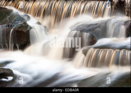 Ein kleines Moor Stream Kaskadierung über ein Wehr mit einer langen Verschlusszeit, um die Bewegung des Wassers zu verwischen erfasst. Stockfoto