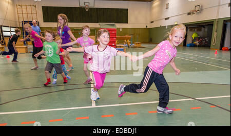 Drei bis elf Jahre alten Mädchen und jungen herumlaufen in einer Sporthalle. Stockfoto