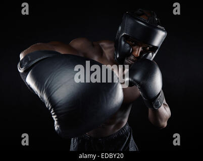 Porträt des jungen männlichen Praktizierenden Boxen auf schwarzem Hintergrund. Afrikanische männlichen Boxer werfen einen Schlag vor. Junge Sportler Stockfoto