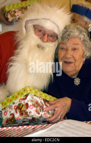 Ältere Menschen, die Geschenke vom Weihnachtsmann am Tag Zentrum an Weihnachten, liphook, Hampshire, UK. Stockfoto