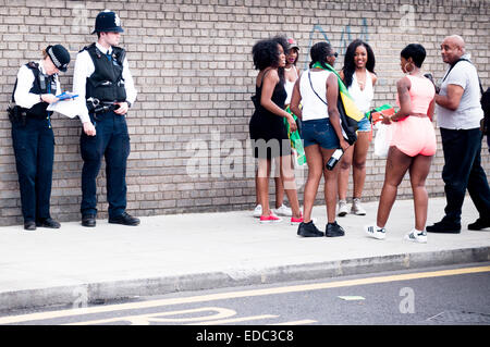 LONDON, UK 24. August 2014: Notting Hill Carnival, Gruppe von Leuten versammelt neben zwei Polizisten stehen Stockfoto