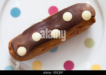 Mark & Spencer Triple Chocolate Polka Dot Eclair auf fleckigen Teller Stockfoto