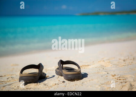 Flip-Flops an einem Sandstrand mit Türkis Wasser hinaus Halfmoon Cay, Bahamas Stockfoto