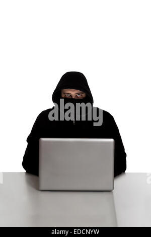 Hacker im schwarzen Kleid auf einem silbernen Laptopcomputer isoliert auf weißem Hintergrund Stockfoto