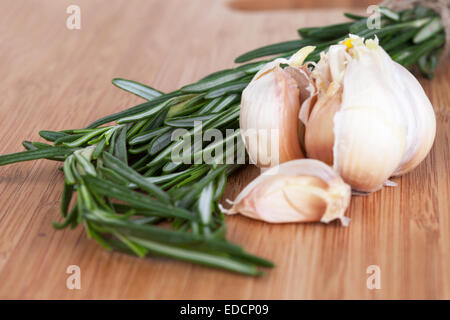 Rosmarin und Knoblauch auf ein Schneidbrett aus Holz Stockfoto