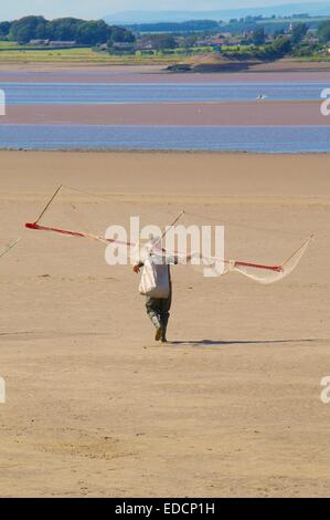 Haaf Net Fischer angeln zu Fuß über das Wattenmeer auf den Fluss-Eden-Kanal. Bownes auf Solway, Solway Mündung, Cumbria, UK Stockfoto