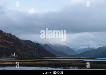 Blick Osten unten Loch Duich in den Schnee bedeckt Berge von Glen Shiel von Ardelve mit Eilean Donan Castle auf der rechten Seite. Stockfoto