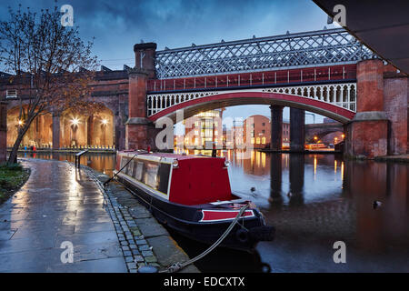 Castlefield Bassin Bereich von Manchester in der Abenddämmerung, ein Kanal Narrowboat Partie am Bridgewater Kanal mit Eisenbahnviadukt hinter Stockfoto