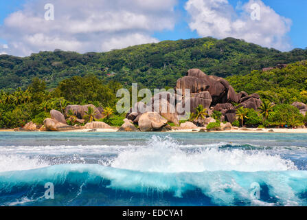 Große Wellen vor Insel von Granitfelsen und einem Hügel auf la Digue, Seychellen. Strand - Anse source d' Argent. Stockfoto