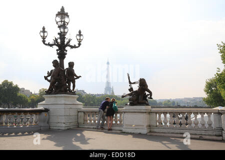 Ein junges Paar auf der Brücke Pont Alexandre III in Paris im Herbst mit dem Eiffelturm hinter, in Frankreich, Europa Stockfoto