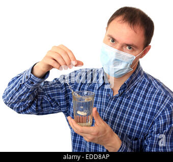 Mann in einer medizinischen Maske löst eine Pille Stockfoto