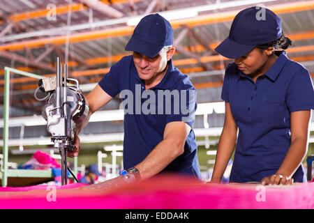 Senior Textil Arbeiter Lehre neuer Mitarbeiter über Schneidstoff Stockfoto