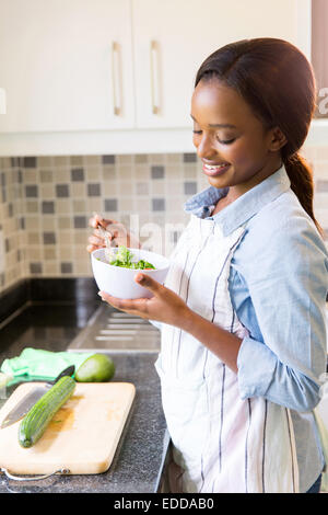 glückliche afrikanischen Hausfrau grünen Salat in der Küche Essen Stockfoto