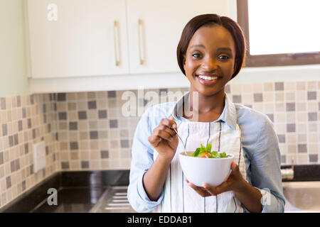 attraktive junge afrikanische Frau mit grünem Salat in Küche Stockfoto