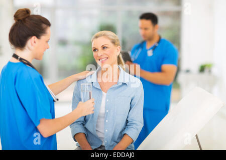 freundliche Krankenschwester geben Patienten Glas Wasser in Arztpraxis Stockfoto