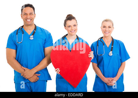 schöne junge Krankenschwester hält Herzform mit Kollegen Stockfoto