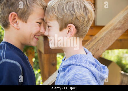 Zwei Brüder in einem Garten, steht man vor einem Baumhaus spielen. Stockfoto