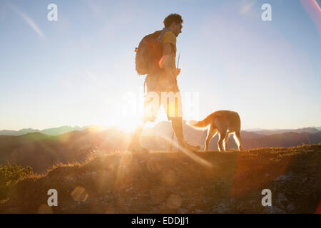 Österreich, Tirol, Unterberghorn, Wanderer mit Hund bei Sonnenaufgang Stockfoto