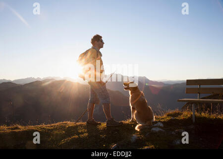 Österreich, Tirol, Unterberghorn, Wanderer mit Hund bei Sonnenaufgang Stockfoto