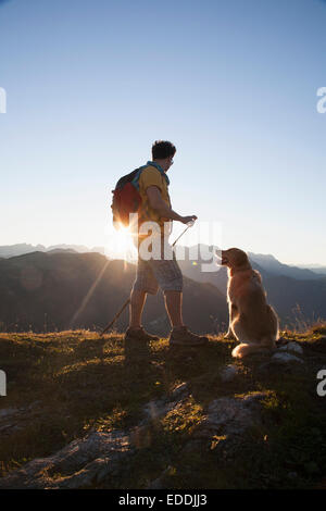 Österreich, Tirol, Unterberghorn, Wanderer mit Hund bei Sonnenaufgang Stockfoto