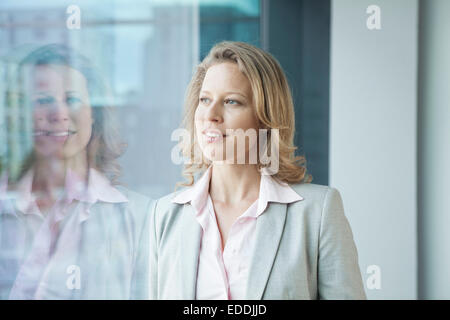 Geschäftsfrau im Büro Blick aus Fenster Stockfoto