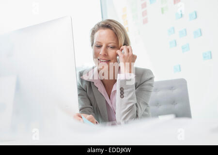 Lächelnde Geschäftsfrau am Telefon im Büro Stockfoto