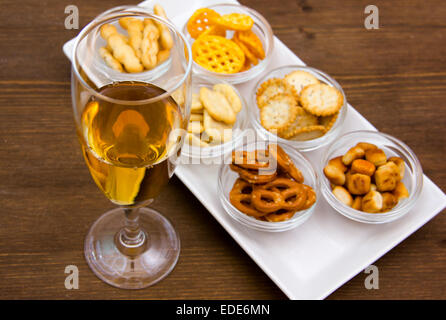 Querflöte mit Aperitif und Brezeln auf Holztisch Stockfoto