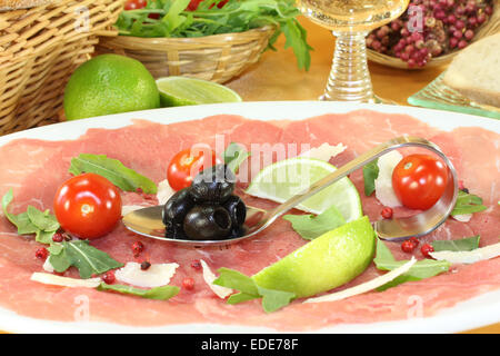 eine Platte mit Carpaccio, Oliven und Rucola Stockfoto
