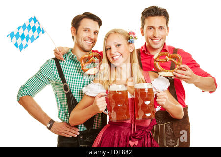 Lächelnde Frau auf dem Oktoberfest tragen zwei Bier Gläser vor zwei Männern Stockfoto