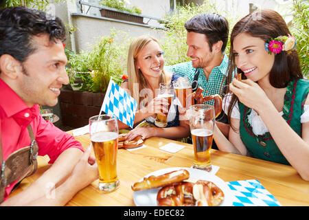 Glückliche Freunde reden und Flirten im Biergarten im Sommer Stockfoto