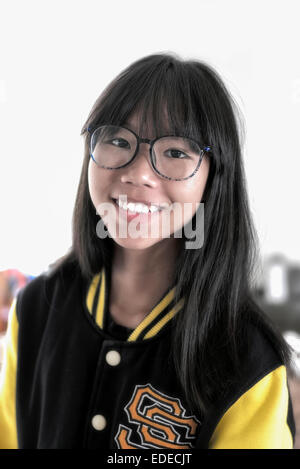 Mädchen trägt eine Brille und eine American College Baseballjacke. Asiatische teen Mädchen Stockfoto