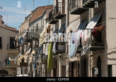 Wasch- und Markisen hängen von Balkonen in einer Straße in der Altstadt am Cefalu-Sizilien-Italien Stockfoto